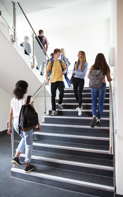High School Students Walking On Stairs Between Lessons In Busy College Building